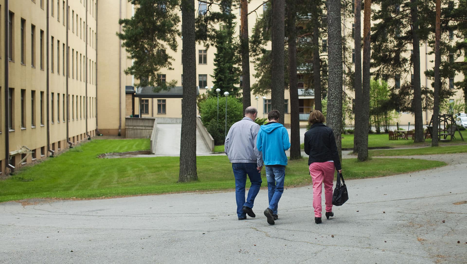 Kuvituskuvassa perhe kävelee asumisyksikön pihalla. Kuva: Laura Vesa