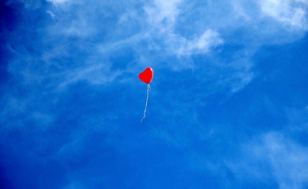 sydämen muotoinen punainen ilmapallo sinistä taivasta vasten