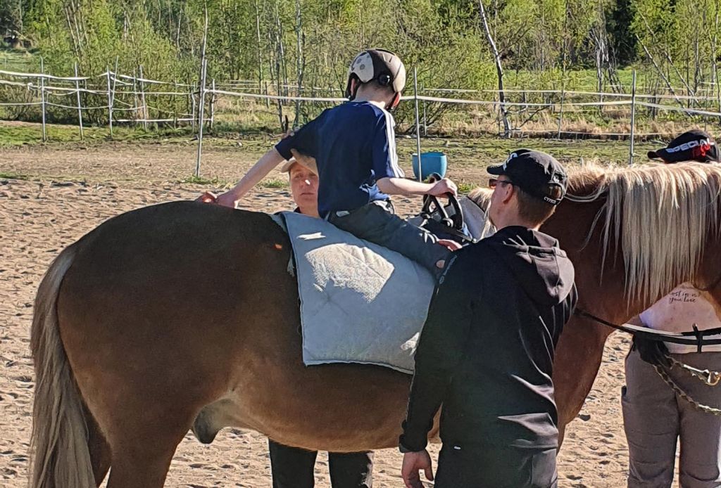 Terapiavyön avulla ratsastaessaan 10-vuotias Olli Juntunen saa kokea ohjaavansa hevosta itse. Kuva: Juntusen perhealbumi