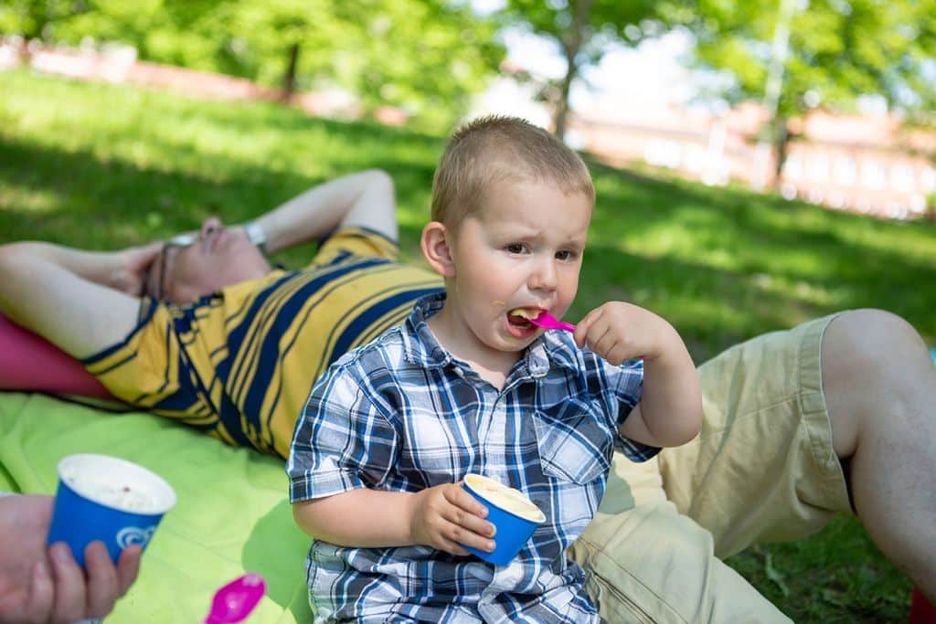 Poika syö jäätelöä, taustalla pojan isä