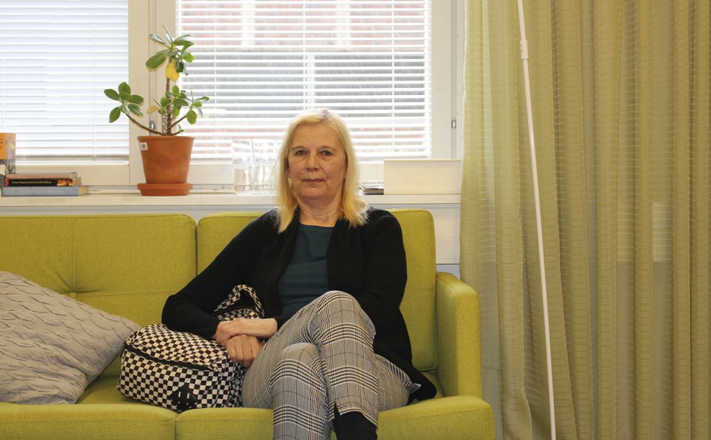 Paula Vesterinen istuu Tulppaanitalolla limen vihreällä sohvalla ja katsoo kameraan.