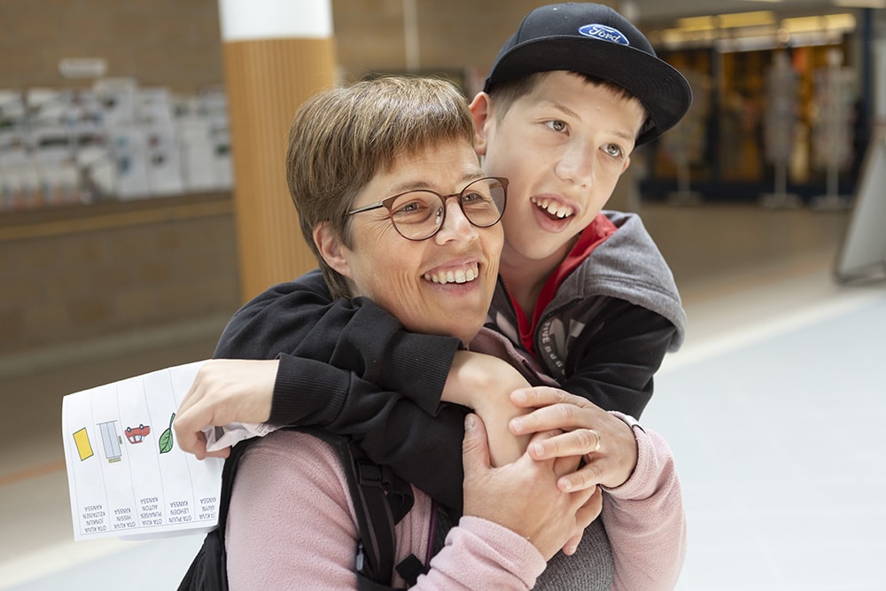 Poika halailee äitiä, molemmat hymyilevät