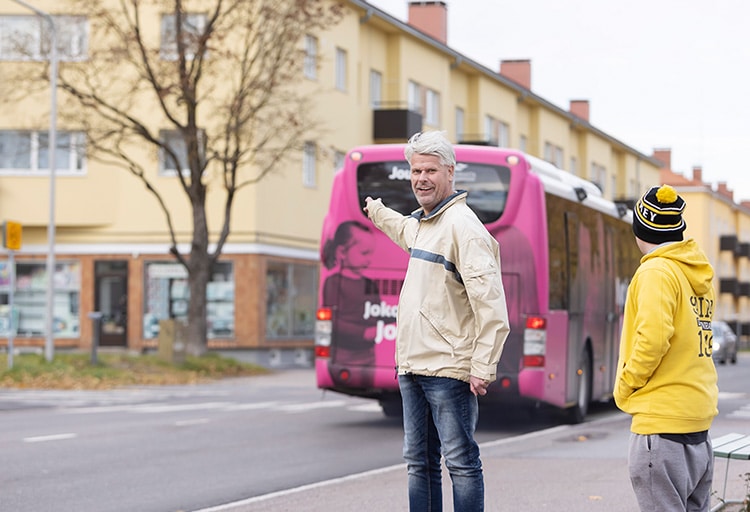 Pekka Saukkonen ja Jyri Lind ovat ulkona kävelykadulla. Pekka osoittaa pinkkiä ohi ajavaa bussia.