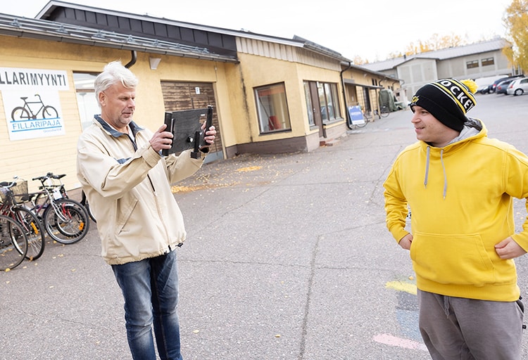 Pekka Saukkonen kuvaa ulkona Jyri Lindiä tabletilla.