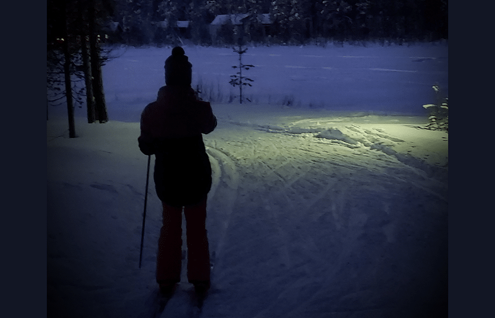 tyttö hiihtää hämärässä metsässä