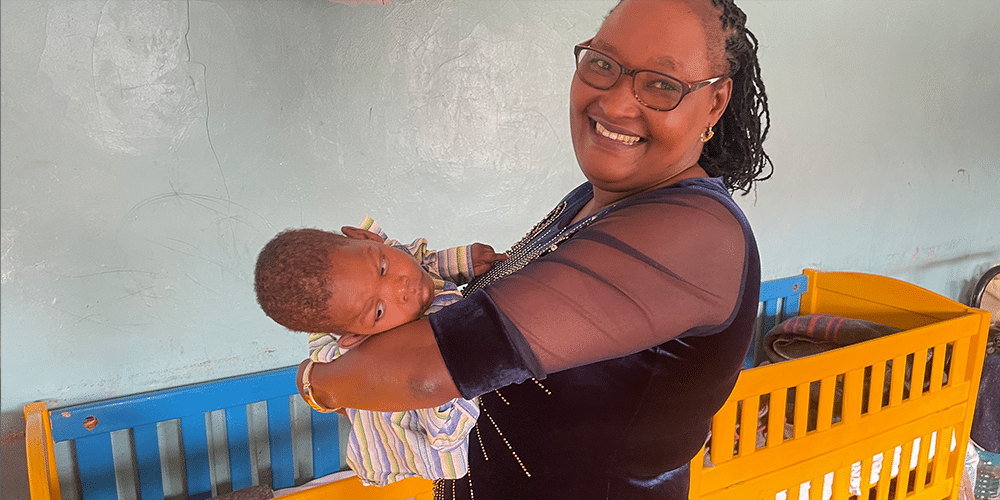 Marion Karimi pitää orpolasta sylissään Hope and Faith -lastenkodissaan Kenian Jujassa.