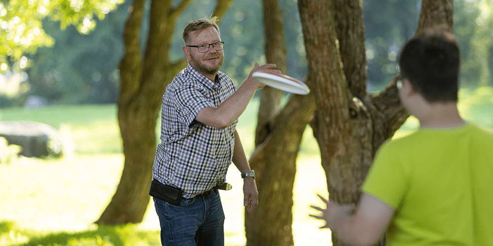 Sijaisisä Petri Hartikainen heittelee frisbeetä sijaisnuorensa kanssa.