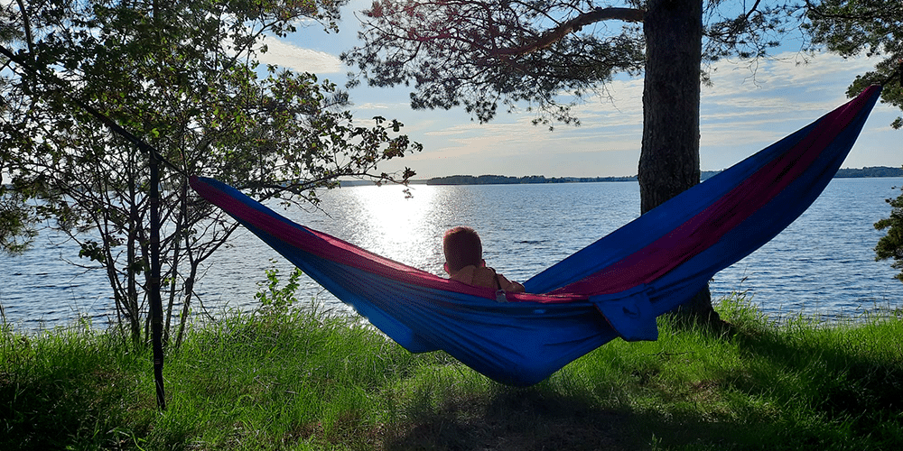 Poika katselee aurinkoiselle järvelle riippumatosta.