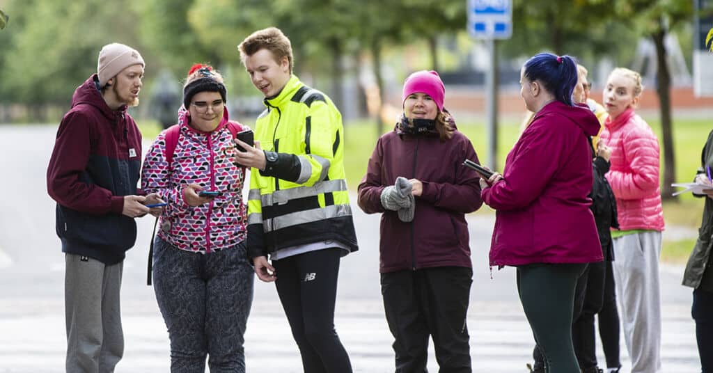 Ryhmä ihmisiä ulkona pelaa Pokemon Go -peliä puhelimilla.