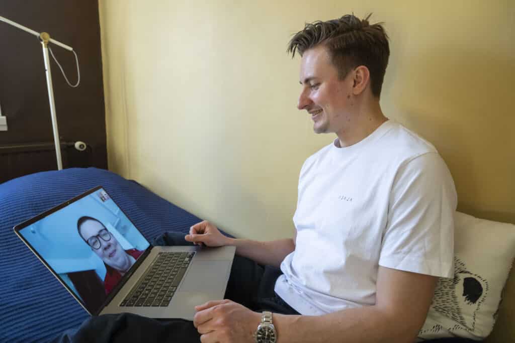 Mies katsoo tietokonneen ruutua ja hymyilee.