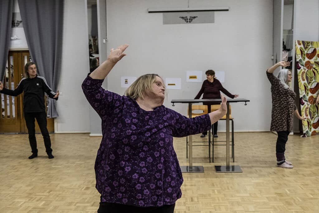Nainen tanssii kädet ylhäällä näytelmän harjoituksissa.