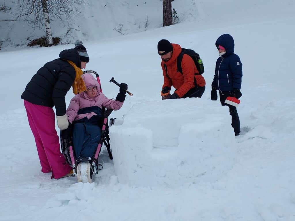 Neljä ihmistä rakentaa lumesta taideteosta.