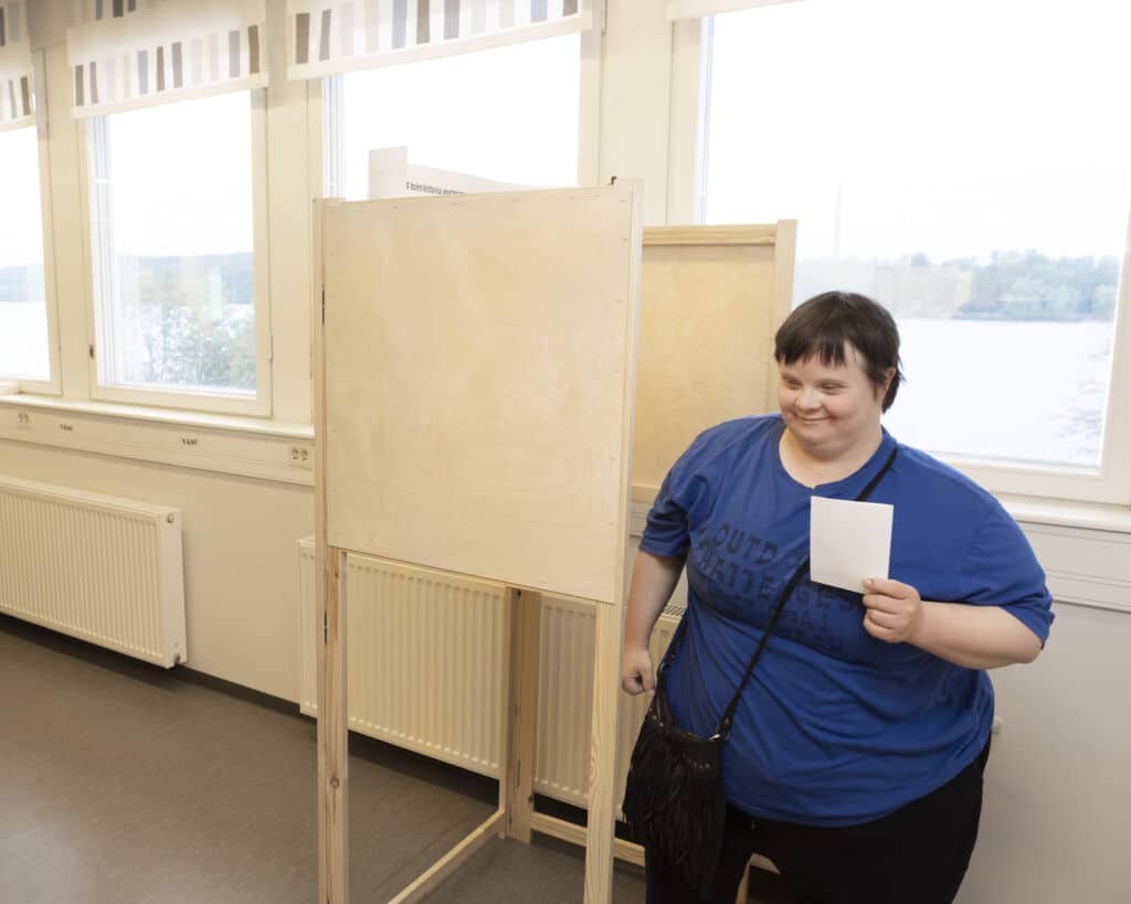 Nainen kävelee pois äänestyskopista lipuke kädessään.